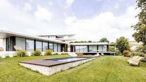 Une maison moderne dotée d’une piscine, d’une pelouse bien entretenue et de mobilier d’extérieur.
