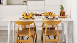 Une cuisine moderne avec des meubles blancs, un îlot central et un luminaire suspendu.