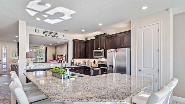 A modern kitchen with dark wood cabinets, stainless steel appliances, and a granite island with seating.