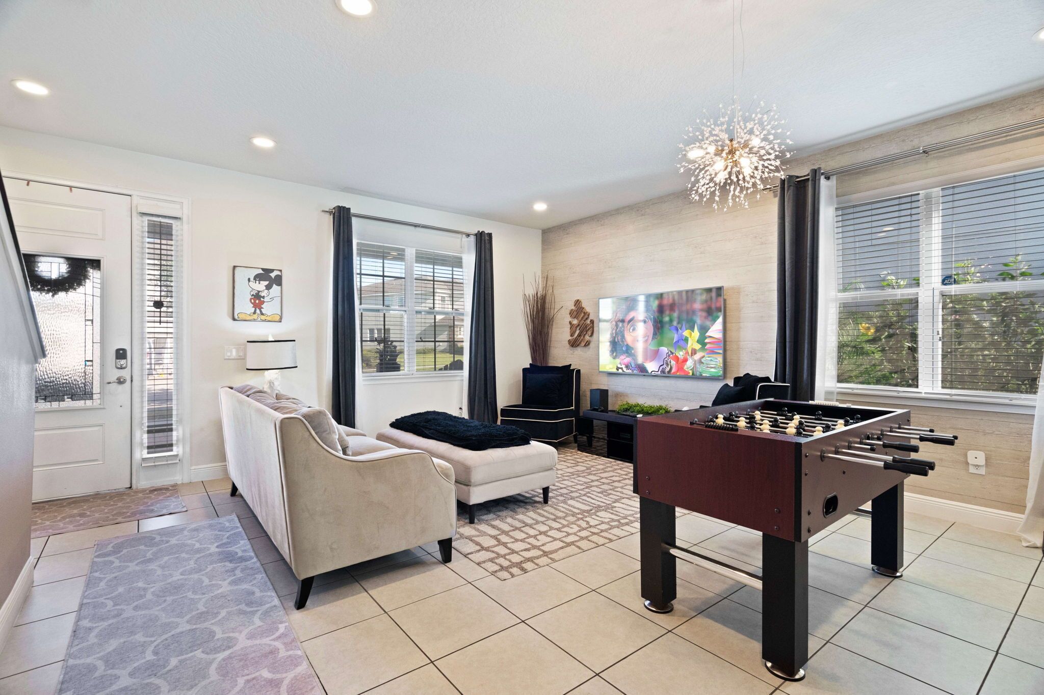 A modern living room with a foosball table, a sofa, a coffee table, and a TV.