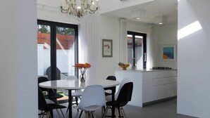 Un comedor moderno con una mesa redonda, sillas y una lámpara de araña.