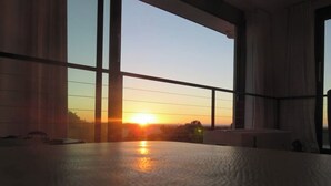 Una habitación con ventanas amplias, vistas al atardecer y suelo de concreto.