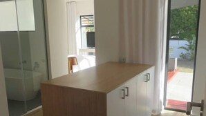 Una cocina moderna con encimera de madera, armarios blancos y una puerta corrediza de vidrio que da a un balcón.