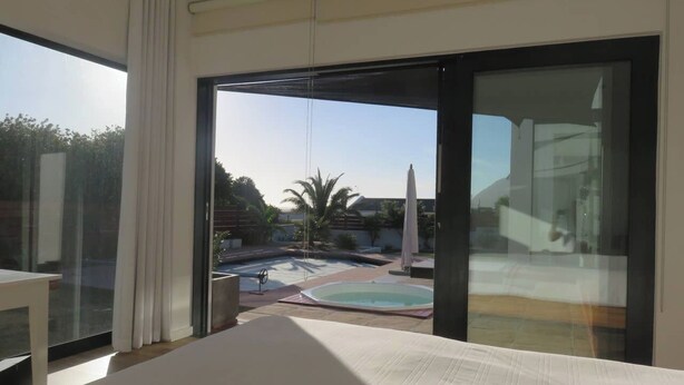 Una habitación con un amplio ventanal corredera que da a una zona de piscina.