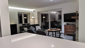 Una sala de estar moderna con una mesa blanca grande, un sofá y un mueble de madera.