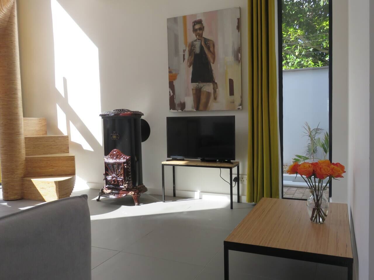 Un soggiorno moderno con televisore, un oggetto decorativo e un vaso con fiori su un tavolo.