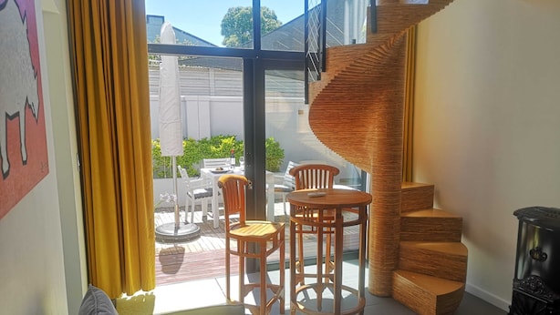 Een moderne woonkamer met een spiltrap, een bank en een eetgedeelte met stoelen en een tafel.