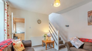 A living room with two brown sofas, a wooden coffee table, a white radiator, and a staircase. - Carraig Dhubh North - UK47125 (Whiting Bay)