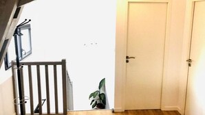 A room with a wooden ceiling, a white door, and a small balcony with a plant. - L'appartement, Gîte 6. Clos des Aigrettes (ST PIERRE D'OLERON)