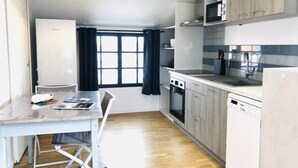 A compact kitchen with a dining area, a microwave, a stove, and a dishwasher. - L'appartement, Gîte 6. Clos des Aigrettes (ST PIERRE D'OLERON)