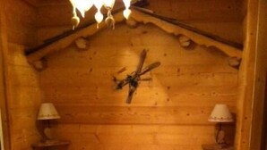 Puisesta hirrestä rakennettu huone, jossa on sänky, kaksi yöpöytää ja kattovalaisin.