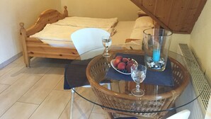 Un dormitori amb un llit de fusta, una taula de vidre amb una cistella i un vas de vidre.