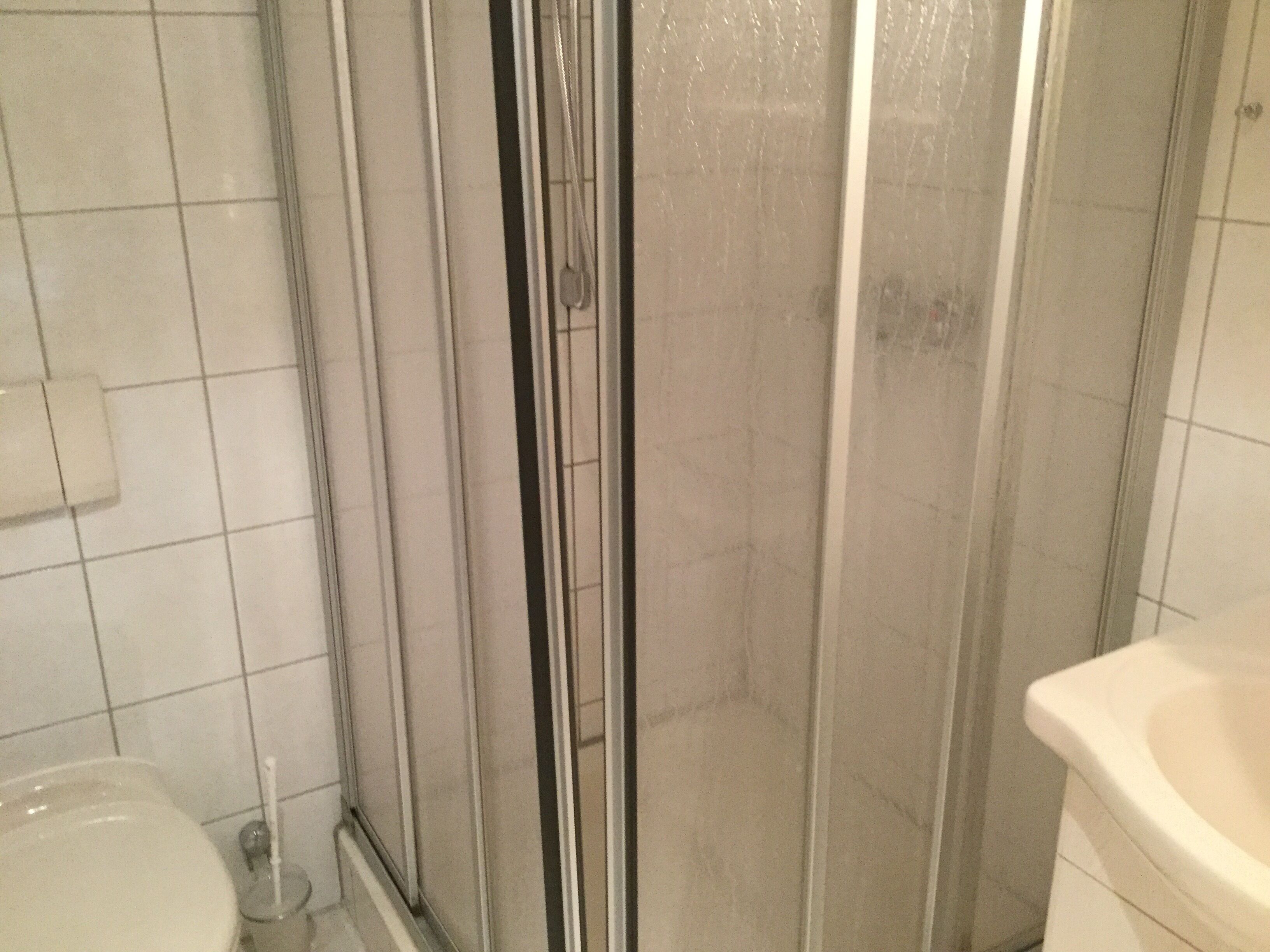 Un baño con cabina de ducha de vidrio, inodoro y lavabo.