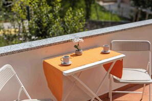 Ein kleiner Tisch im Freien mit einem weißen Stuhl auf jeder Seite. Auf dem Tisch steht eine Topfpflanze.