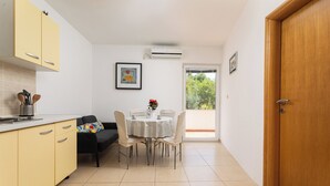 A compact kitchen with yellow cabinets, a dining table with chairs, and a small window.