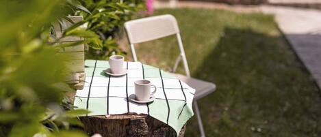 A table set outdoors with a checkered tablecloth, two white cups, and saucers.