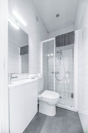 Une salle de bain moderne avec une douche à parois de verre, des toilettes blanches et un meuble-lavabo avec un miroir et un évier.