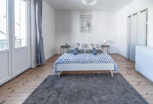 Une chambre à coucher avec un lit, un tapis, une table de chevet, une lampe et une œuvre d’art encadrée accrochée au mur.