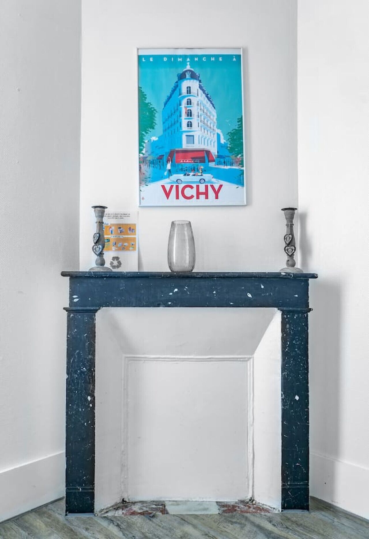 A white wall with a framed poster of a building and the word "VICHY" below it.