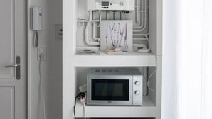 A compact kitchen with a built-in microwave, oven, and water heater. - Quiet and cosy apartment, free parking (Vichy)