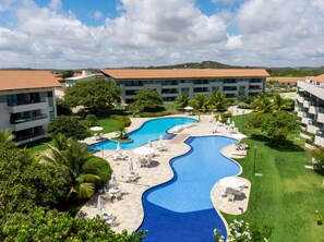 Ein Resort mit großem Schwimmbad, mehreren Gebäuden und üppiger Bepflanzung.