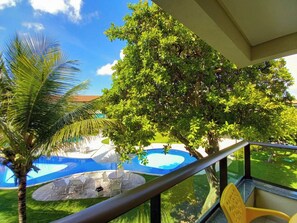 Un espace piscine agrémenté d’un palmier, d’un grand arbre et offrant une vue sur un bâtiment.