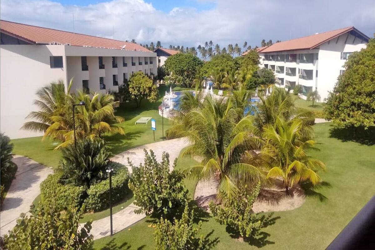 A hotel courtyard with a swimming pool, palm trees, and a fountain.