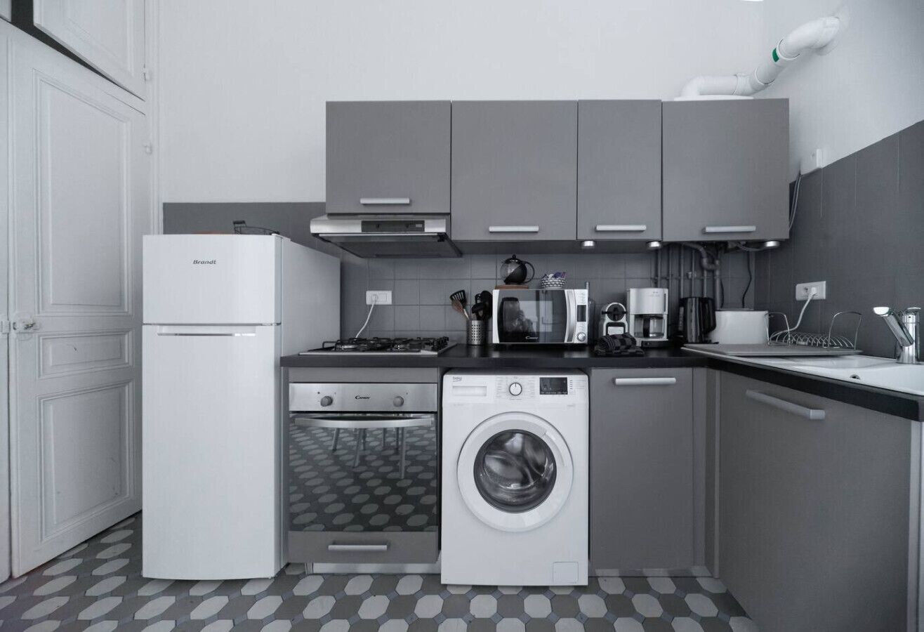 A compact kitchen with a refrigerator, oven, microwave, and washing machine.