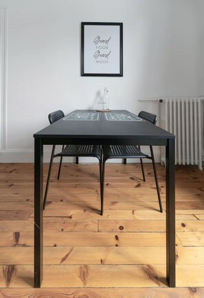 A dining table with chairs, a framed quote on the wall, and a radiator in the background. - Appartement lumineux en centre ville avec parking (Vichy)