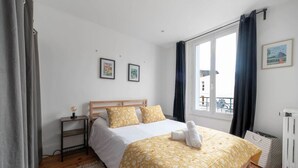 Une chambre à coucher avec un lit en bois, une table de chevet avec une lampe et une fenêtre avec des rideaux.