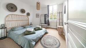 Une chambre à coucher comprenant un lit, une fenêtre, un radiateur, une table de chevet et une étagère fixée au mur.