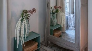 A hallway with a vintage armoire, a teal console table with vases, and two framed pictures on the wall. - Superbe studio avec terrasse dans immeuble classé (Vichy)