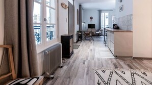 Amplia sala de estar con piso de madera, cocina con mostrador y comedor con sillas.