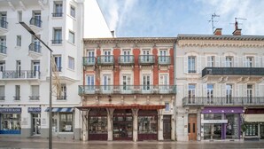 Una hilera de edificios de estilo europeo con locales comerciales en la planta baja, incluyendo una peluquería y una boutique.