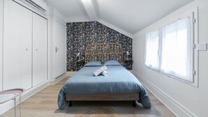 Un dormitorio con cama, armario, ventana y pared con diseño.