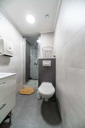 Un baño pequeño con inodoro, ducha y lavamanos.
