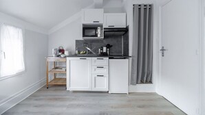 Una cocina compacta con muebles blancos, un microondas y un lavamanos.