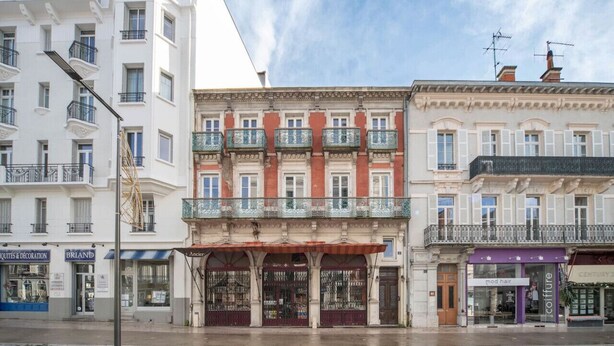 A row of European-style buildings with shops on the ground floor, including a hair salon and a boutique.