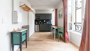A narrow hallway leading to a kitchen with a dining area.