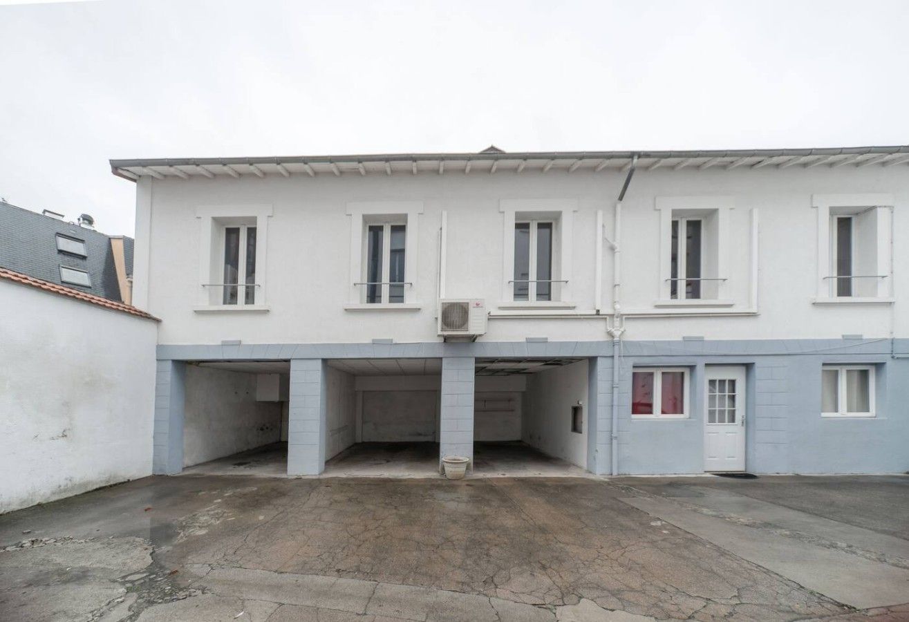 A two-story building with a flat roof, multiple windows, and a central entrance.