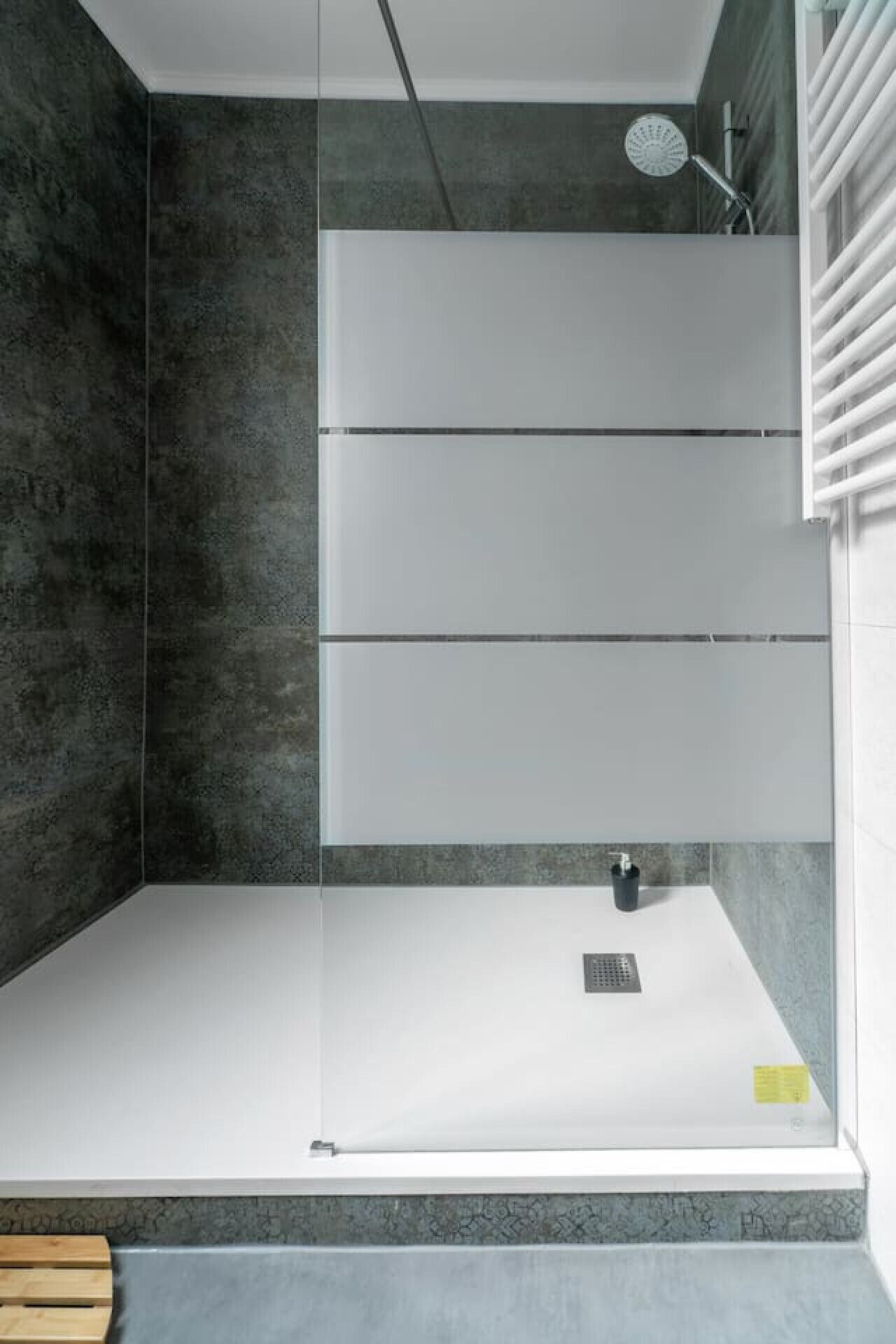 A modern shower enclosure with a glass door, a built-in seat, and a handheld showerhead.