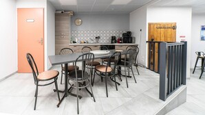 Una cocina moderna con comedor, que incluye una mesa grande con sillas, una cafetera y un microondas.