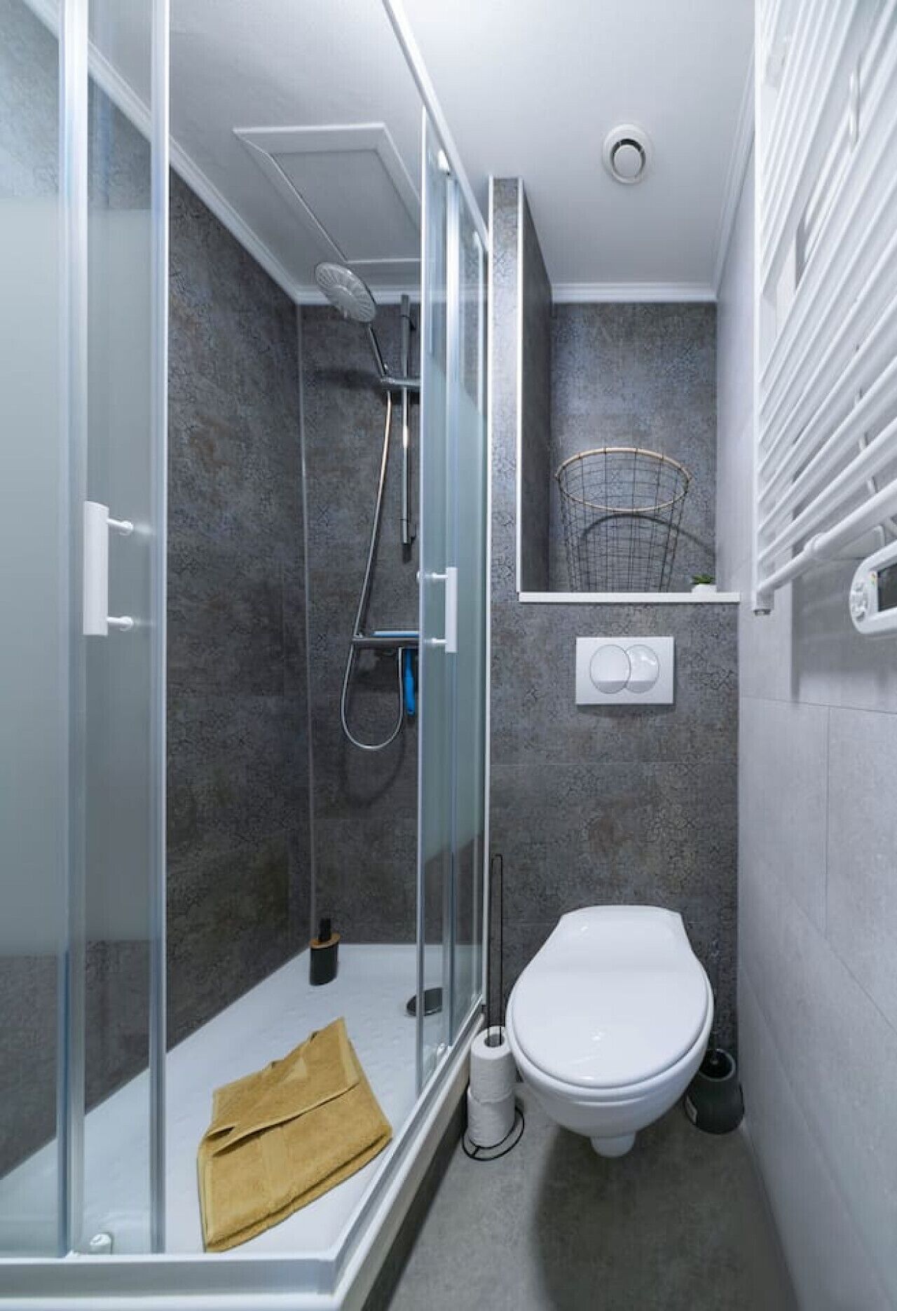 A modern bathroom with a glass-enclosed shower, a toilet, and a towel rack.