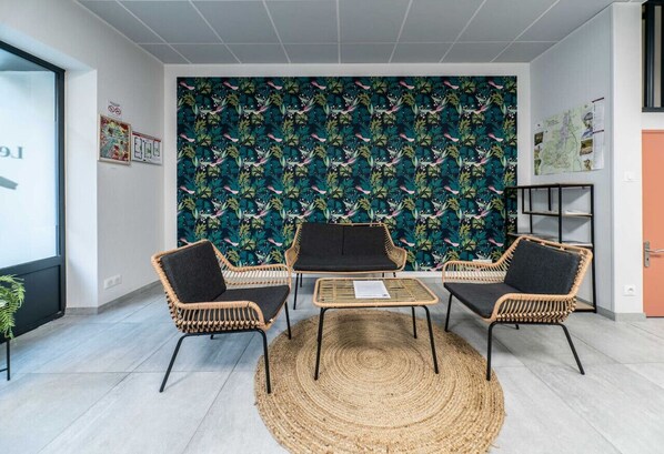 A room with a large window, a woven rug, and a wall with a tropical leaf pattern.