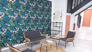 A lobby with wicker furniture, a woven rug, and a wall with a tropical leaf pattern. - Grande Maison de ville design avec parking gratuit (Gannat)