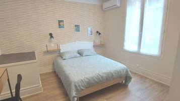 Ein Schlafzimmer mit Bett, Schreibtisch und Fenster.