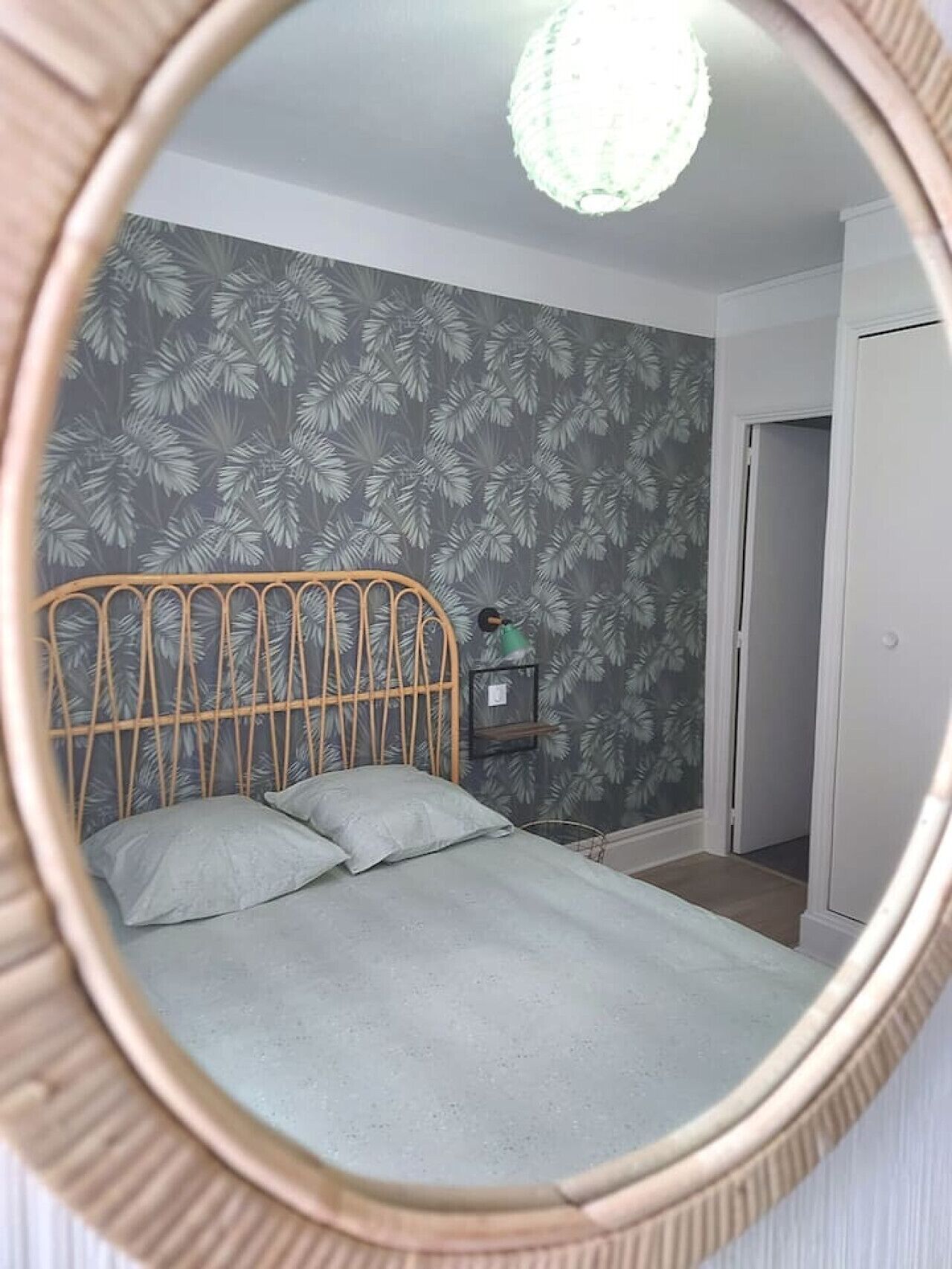 A bedroom with a bed, a mirror, and a door.