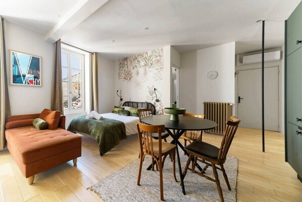 Une chambre moderne comprenant un lit, un canapé, une table à manger avec des chaises et un radiateur.