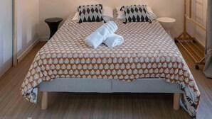 Un dormitorio moderno con una cama grande, un aplique en la pared y una escalera de madera.