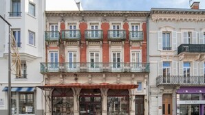 Une rangée de bâtiments, dont le bâtiment central se distingue par sa façade rouge et ses nombreux balcons.